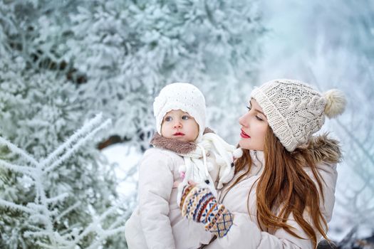 Young mother holding a daughter in a winter forest for a walk