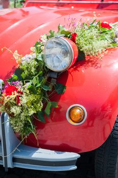 Front of a red wedding car with flower bouquet