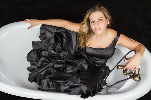 Portrait of beautiful fashion girl with black spanish flamenco dress posing in a vintage bathtub