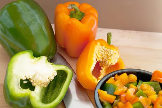 Sliced and diced Green and Orange Peppers on a cutting board and in a black bowl