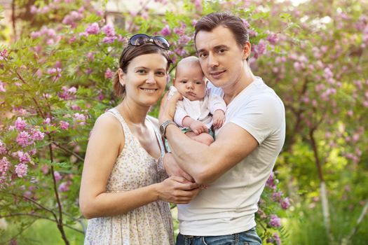 Young couple with newborn son outdoors in spring