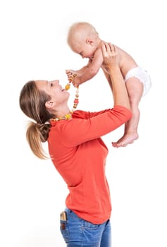 Young Caucasian woman lifting her baby son over white, boy playing with nursing necklace