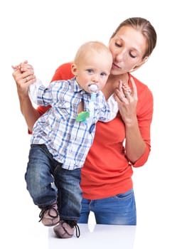 Baby boy learning to walk with mother's help over white background