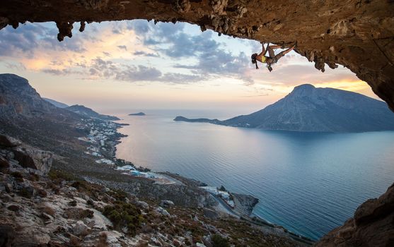 Female rock climber against picturesque view of Telendos Island at sunset. Kalymnos Island, Greece.