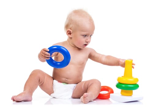 Cute little boy playing with pyramid toy over white background