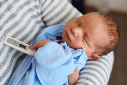 Father taking newborn son's temperature with thermometer