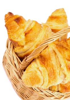 Freshly Baked Croissants in Wicker Basket closeup on white background