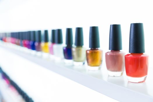 colorful nail polish colors in a row at nails saloon on white background