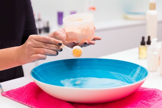 Nail saloon preparing exfoliant skin renewal scrub bath in bowl water