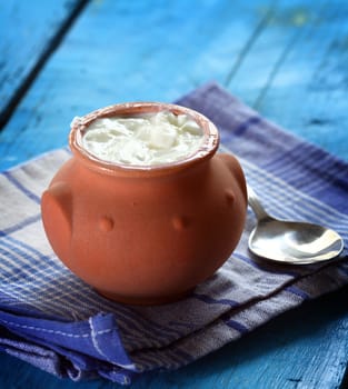 Homemade yogurt in a ceramic pot and spoon
