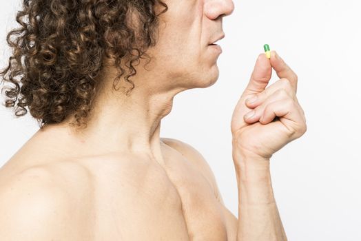 Cropped shot of bare chested mediterranean man taking colourful pill
