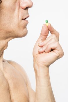 Cropped shot of bare chested mediterranean man taking colourful pill