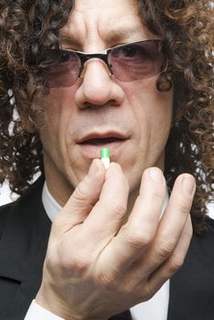 Cropped shot mediterranean man in a suit taking colourful pill