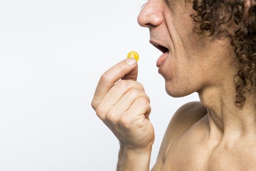 Cropped shot of bare chested mediterranean man taking colourful pill
