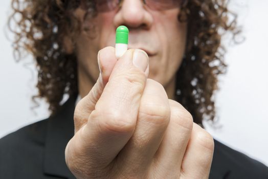 Cropped shot of mediterranean man in a suit holding colourful pill