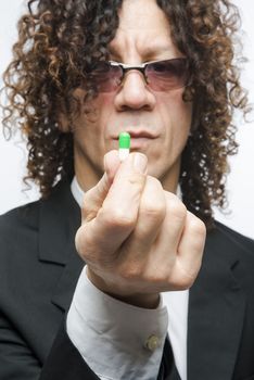 Cropped shot of mediterranean man in a suit holding colourful pill