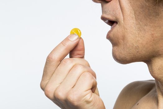 Cropped shot of bare chested mediterranean man taking colourful pill