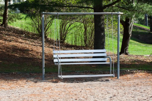 A lone Swinging Bench in the Park waits for someone to sit down.