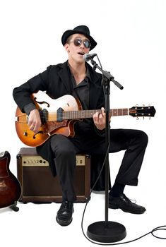 the guitarist sings sitting on one amplifier isolated on white background