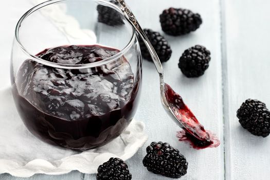 Messy spoon with blackberry jelly on a blue table. Extreme shallow depth of field and selective focus on jelly on spoon.