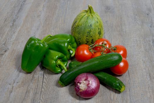 assortment of seasonal vegetables consisting of onions, zucchini, peppers, tomatoes and cucumber