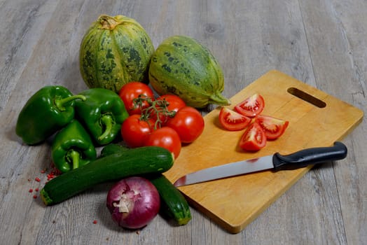 assortment of seasonal vegetables consisting of onions, zucchini, peppers, tomatoes and cucumber
