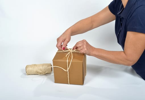 Cardboard packing a young woman with a spool of string
