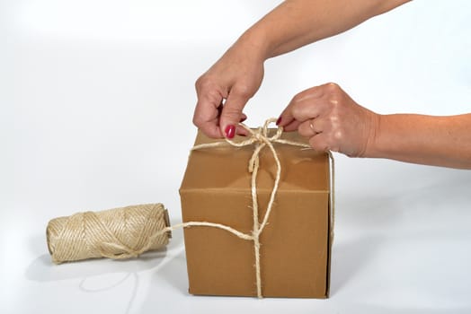 Cardboard packing a young woman with a spool of string
