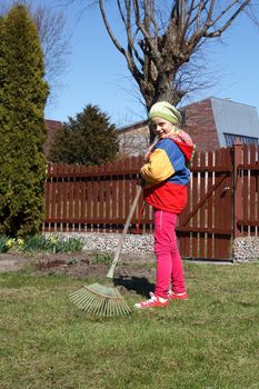 young girl working in the garden with rake