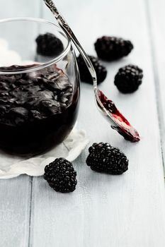 Messy spoon with blackberry preserves on a blue table. Extreme shallow depth of field.