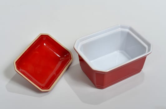 small red porcelain bowl set on a white surface
