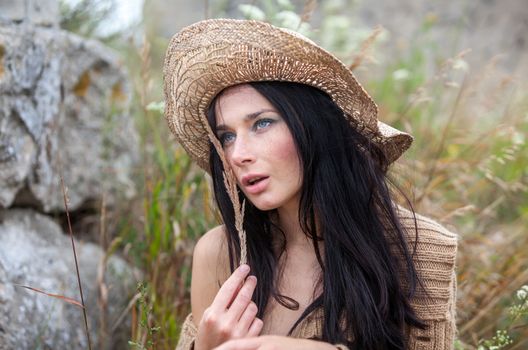 Portrait of a girl in straw hat against soft nature background