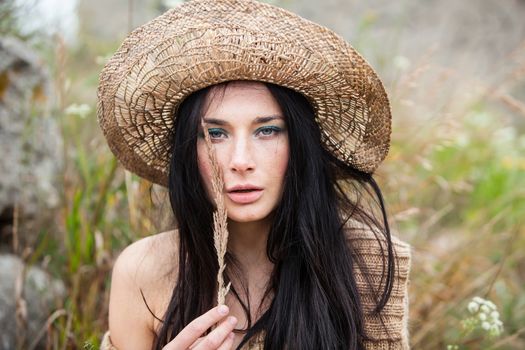 Portrait of a girl in straw hat against soft nature background