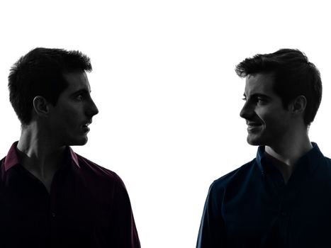 two caucasian young men twin brother friends looking at each others in shadow white background