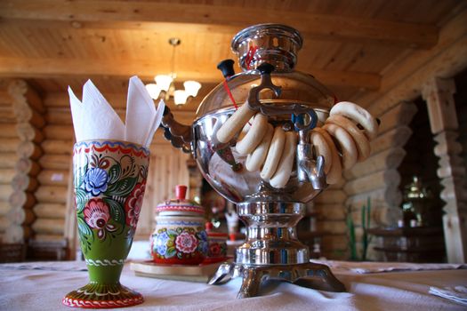Russian tea drinking with samovar and bread rolls in a traditional timber house