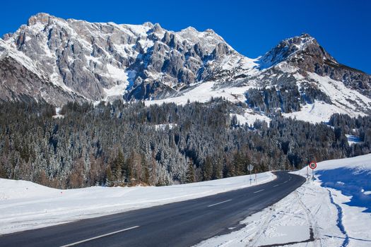 Winter in the alps mountain. Asphalt road among snow.