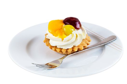 Sweet cupcake with fruits and whipped cream on plate with fork isolated on white background