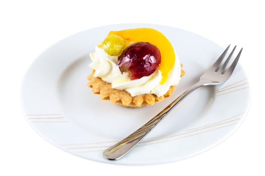 Sweet cupcake with fruits and whipped cream on plate with fork isolated on white background