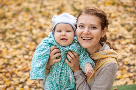 Portrait of young woman and her baby son in autumn park