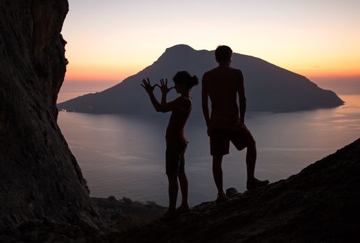 Silhouettes of two young people having fun at sunset, Kalymnos island, Greece