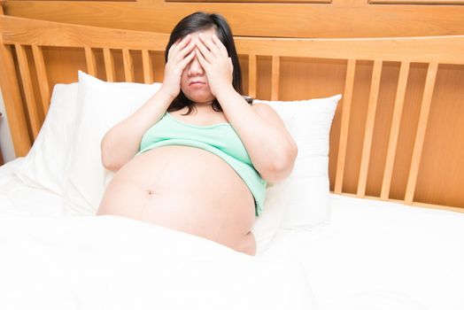 Young thai pregnant woman under stress in bed