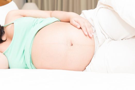 Young Thai pregnant woman sleeping in bed, taken in door