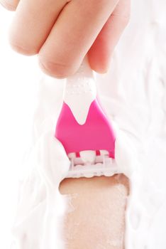 Close up on woman shaving her legs. Over white.