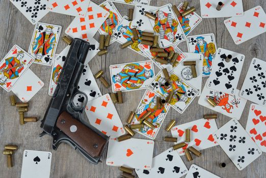 gun with somes bullets on the table with playing cards