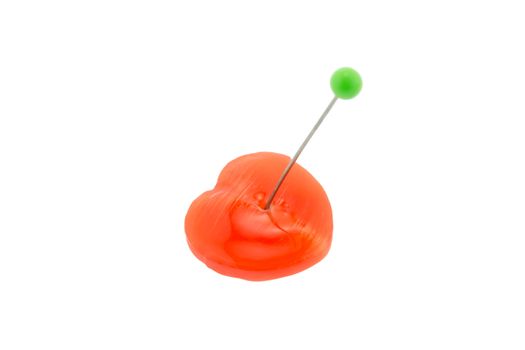 Orange heart candy is stabbed with the green pin on white background. Heart for Valentine and love story