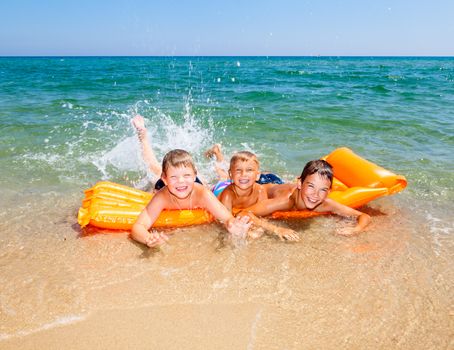 Three kids splashing water on a beach