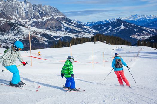 Ski, winter, snow, skiers, sun and fun - family enjoying winter vacations. Back view.