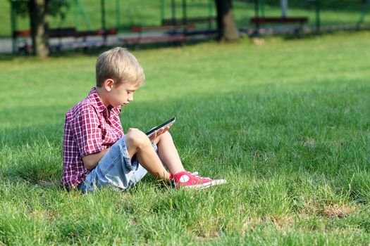 boy sitting on grass and play with tablet pc