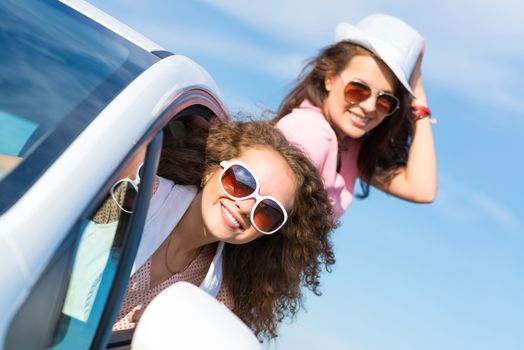 young attractive woman in sunglasses got out of the car window and laugh