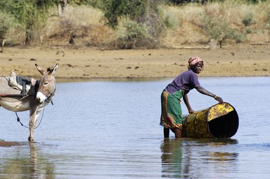 filling and transportation of water bottles at lake is for women to irrigate crops